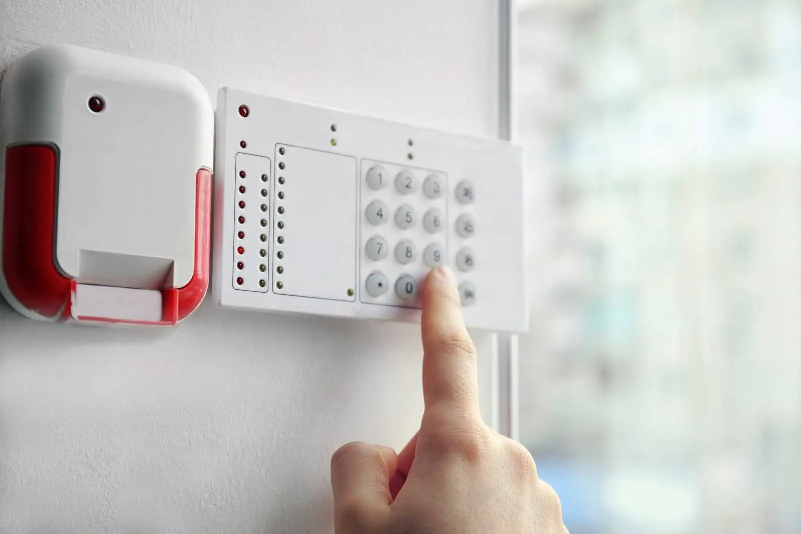 A person’s hand pressing the numbers on a security alarm keypad.