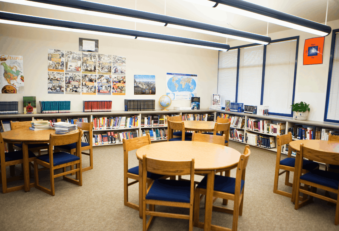 Bright school library with study tables and bookshelves, illustrating a typical educational environment where CCTV monitoring and GDPR compliance are important for safeguarding and privacy protection.